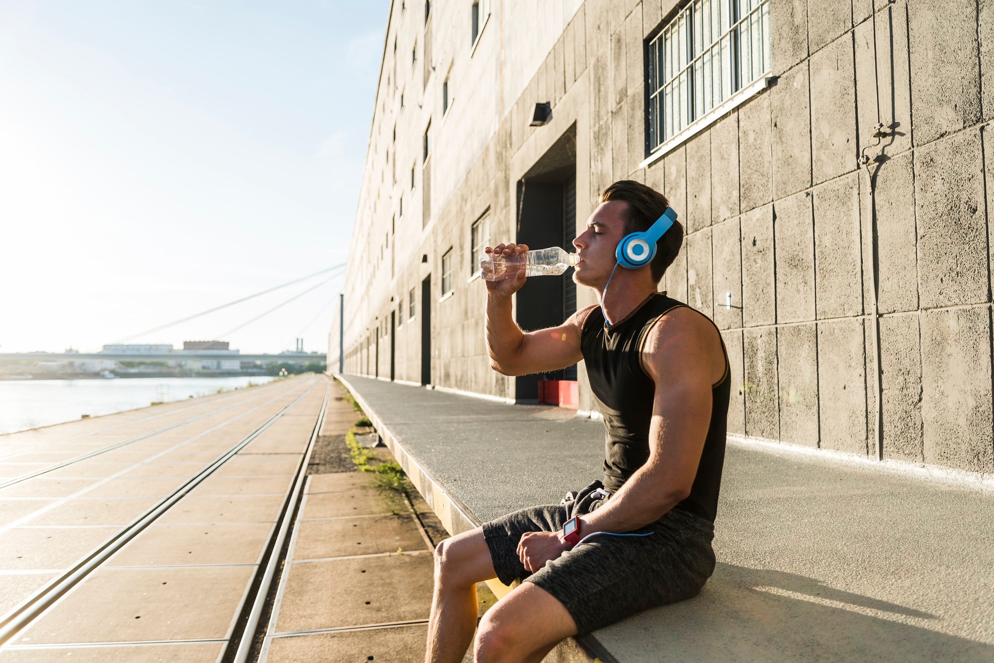 Young athlete wearing headphones, sitting on a wall